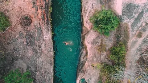 Drone view of a person bathing in a very blue natural water channel in a zeni Stock Footage 218048204