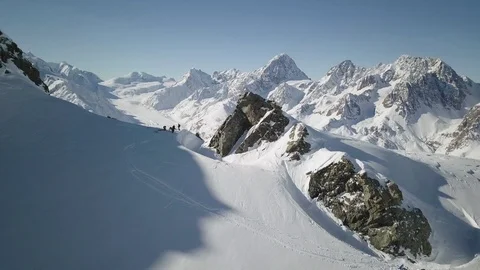 Drone view pro athletes standing on top of snowy mountain with blue sky panorama Stock Footage 121580596