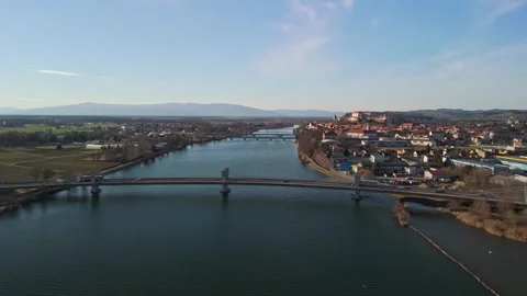 Drone view of Ptuj's castle, old town rooftops, river bridges, and nearby hills Vidéo 332753847