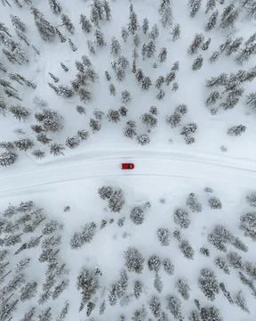 Drone view of a red car driving though a snowy forest in Lapland, Finland Stock Photos