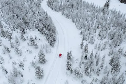 Drone view of a red car driving though a snowy forest in Lapland, Finland Stock Photos
