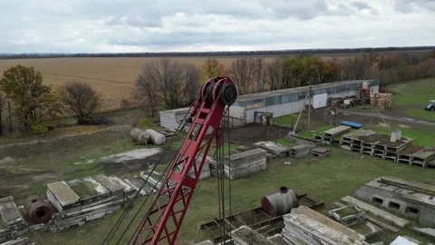 Drone view of red crane boom above construction yard and fields Stock-Footage 348263787