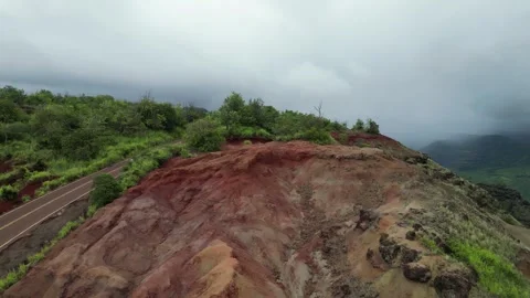 Drone view of a red earth hillside with a winding road in Hawaii Stock-Footage 348251076