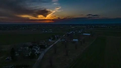 Drone View of a Red Sunset, Peaking Thru Clouds, Looking Over Rural Countryside Foto stock
