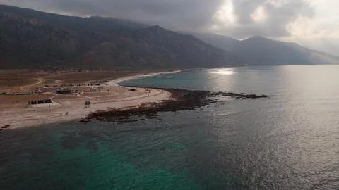 Drone view of remote beach and mountains under dramatic clouds Stock Photos