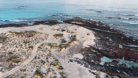Drone view of remote beach with off-road vehicles and turquoise sea Stock Footage 327921892