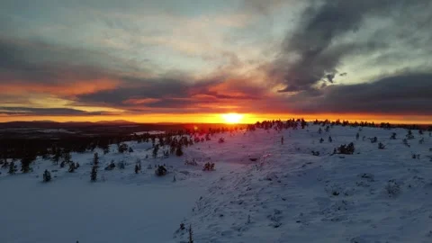 Drone view revealing winter sunset behind snowy mountain and forests in Lapland Stock Footage 301330774