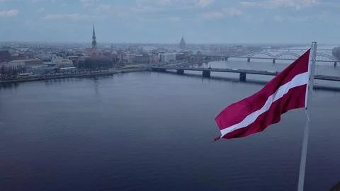 Drone View Of Riga Old Town With Latvian Flag Waving In Foreground Aerial Pan Fotos de archivo