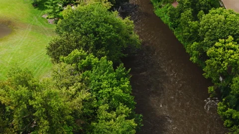 Drone view of a river running between residential buildings and a gree Stock-Footage 327883806