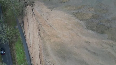 Drone view of road beside quiet beach with cars and scattered dark patches in Stock Footage 306441043