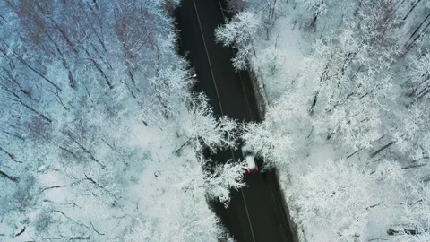 Drone view of a road going through a winter, snow-covered forest Stock Footage 122654116