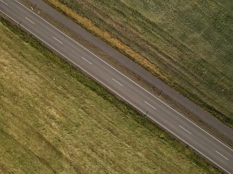 Drone view of a road in the landscape between mowed grass fields Stock Photos
