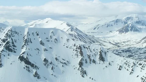 Drone view of rocky mountains covered in snow with cloudy sky located in Iceland Stock Footage 124229812
