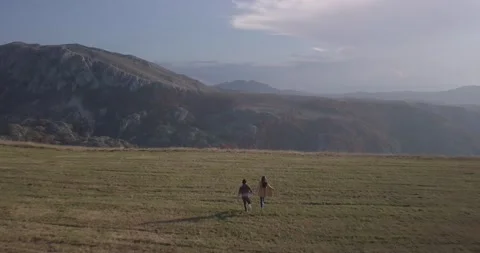 Drone view romantic couple man and woman run in field in mountains Montenegro Stock Footage 144986703