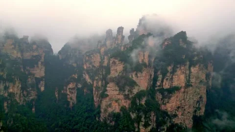 Drone view of Sandstone karst Formations Cloaked In Thick Fog And Lush Foliage Video stock 339335253