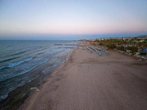 Drone View of Sandy Beach with Rows of Sunbeds and Palm Trees in Crete 스톡 사진