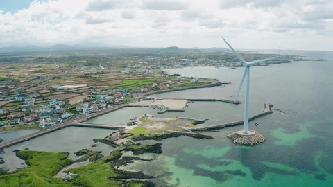 Drone View. Scenery of a seaside town with wind turbines running. Jeju Island in Stock Footage 113999545
