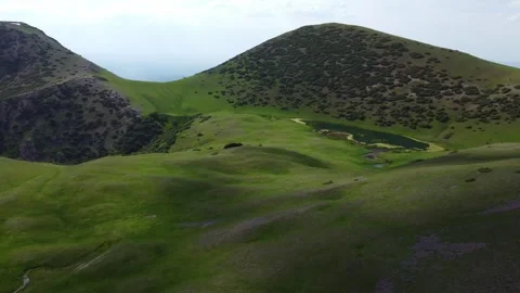 Drone view of scenic alpine Silbeli lake between rolling green hills in Kazakhst 스톡 동영상 337135993