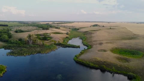 Drone view of a serene river flowing through vibrant fields and a lush landscape Stock Footage 282725795