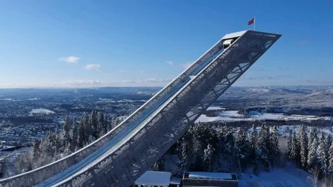 Drone view on ski jump in Norway on a frozen winter day with waving flag Stock Footage 125293237