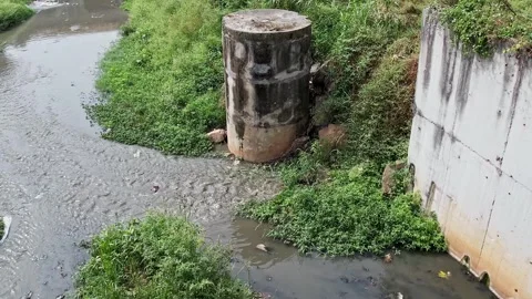 Drone view of a small drainage canal overflowing dirty smelling water and s.. Video stock 335266563