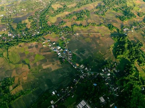 Drone view of small settlement below jungle mountain at dusk Stock Photos