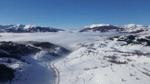 Drone View of Snow Covered Mountain Peaks with Fog Filled Valley 스톡 동영상 338989547