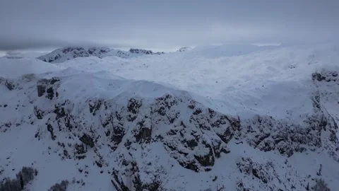 Drone View of Snow-Covered Mountain Peaks Under a Cloudy Winter Sky Stock Footage 341960983