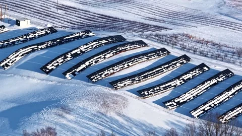 Drone view of a snow-covered solar farm in winter countryside, showing 動画素材 334000494