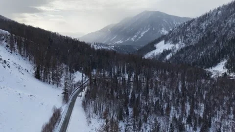 Drone view of snowy forest road through mountain valley in Xinjiang Stock Footage 336599061