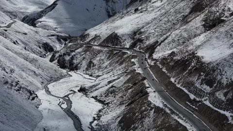 Drone view of snowy mountain road and frozen valley in Xinjiang China Stock Footage 337888307