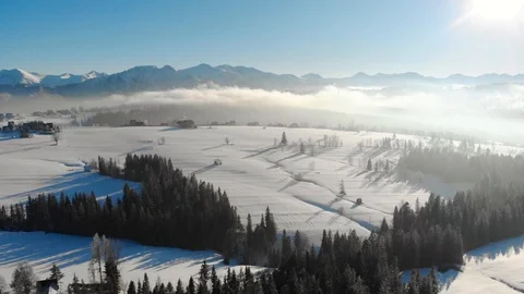 Drone view of snowy valley in mountains with trees in haze and bright sunlight Vidéo 105686089