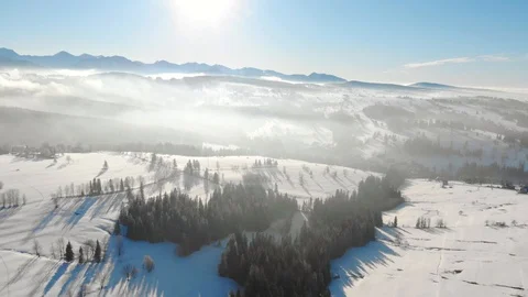 Drone view of snowy valley in mountains with trees in haze and bright sunlight 스톡 동영상 105686802