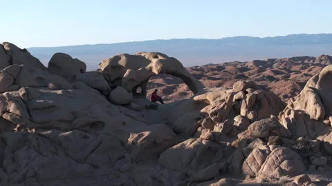 Drone View Of Stone Arch With Alone Tourist Sitting Inside, At National Park Stock Footage 310219065