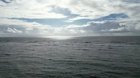 Drone view of sun glinting through clouds over a dark ocean in Hawaii Stock-Footage 348263761