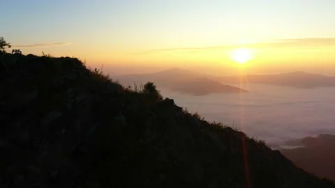 Drone view, Sun rises from behind mountain top, fog moves and rises Vídeos de archivo 221922651