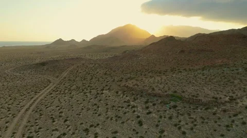 Drone view Sunbeams over rugged coastal mountains, turquoise sea at golden hour Vídeo Stock 337956188