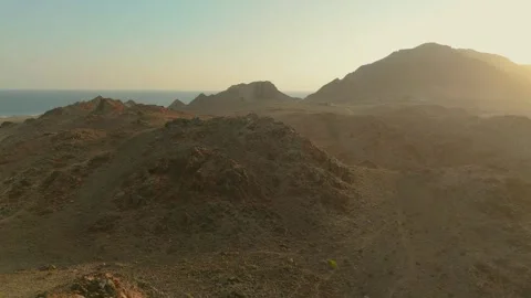 Drone view Sunbeams over rugged coastal mountains, turquoise sea at golden hour Stock Footage 337956437