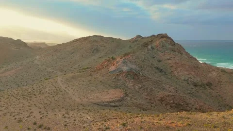 Drone view Sunbeams over rugged coastal mountains, turquoise sea at golden hour Video stock 337956583