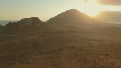 Drone view Sunbeams over rugged coastal mountains, turquoise sea at golden hour Video stock 337956861
