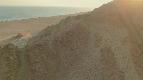 Drone view Sunbeams over rugged coastal mountains, turquoise sea at golden hour Video stock 337957347