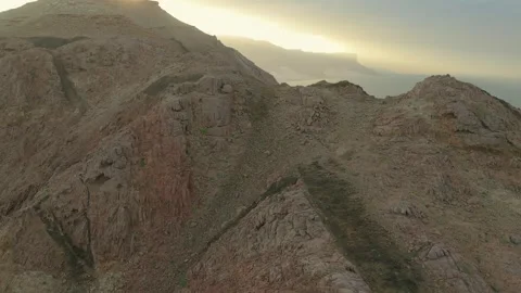 Drone view Sunbeams over rugged coastal mountains, turquoise sea at golden hour Video stock 337957433