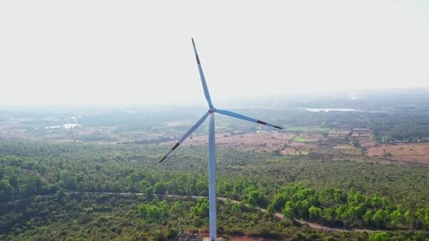 A drone view of a tall wind turbine stand against misty sky surrounded by l.. Stock Footage 346703828