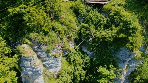 Drone view three people riding on zipline in Sochi Skypark Stock Footage 112213199
