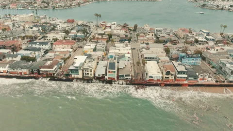 Drone view of tightly packed beachfront homes beside rising surf  Stock Footage 347621553