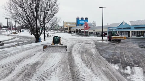 Drone view of tractor clearing snow and ice from shopping center parking lot in Stock-Footage 332123839