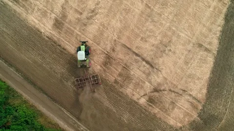 Drone view of a tractor plows the land after harvesting wheat. The tractor turns 스톡 동영상 248049720