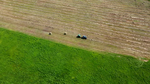 Drone view of a tractor working in a field with haystacks Stock Footage 234167177