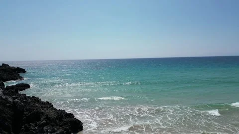 Drone view of turquoise surf breaking on black lava rocks in Hawaii Stockbeeldmateriaal 347825789