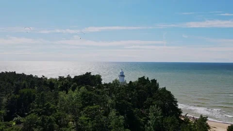 Drone View of Uzava Lighthouse with Baltic Sea and Paragliders - Scenic Stock Footage 295107931